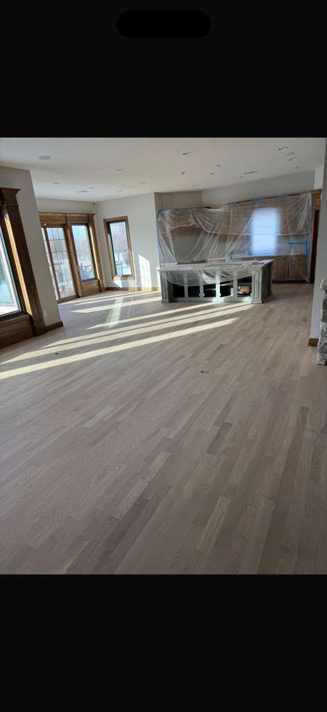 Wide hardwood floor refinished in a large living area